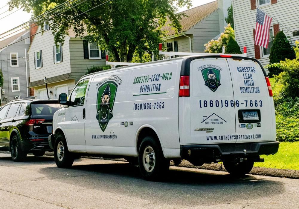 A white van is parked on the side of the road in front of a house.