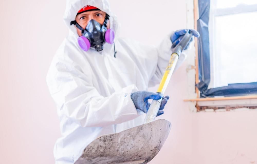A man in a protective suit and mask is holding a shovel.