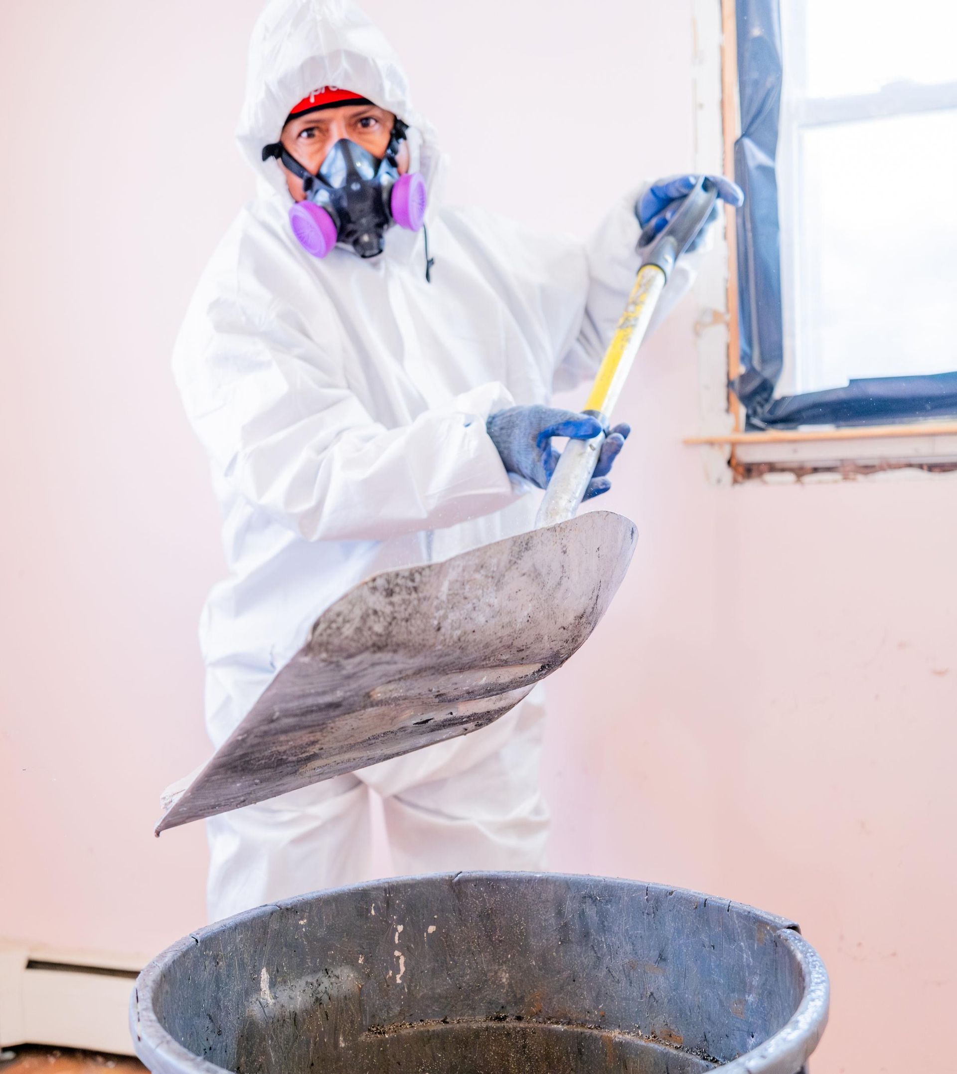 A man in a protective suit disposing of asbestos-containing material