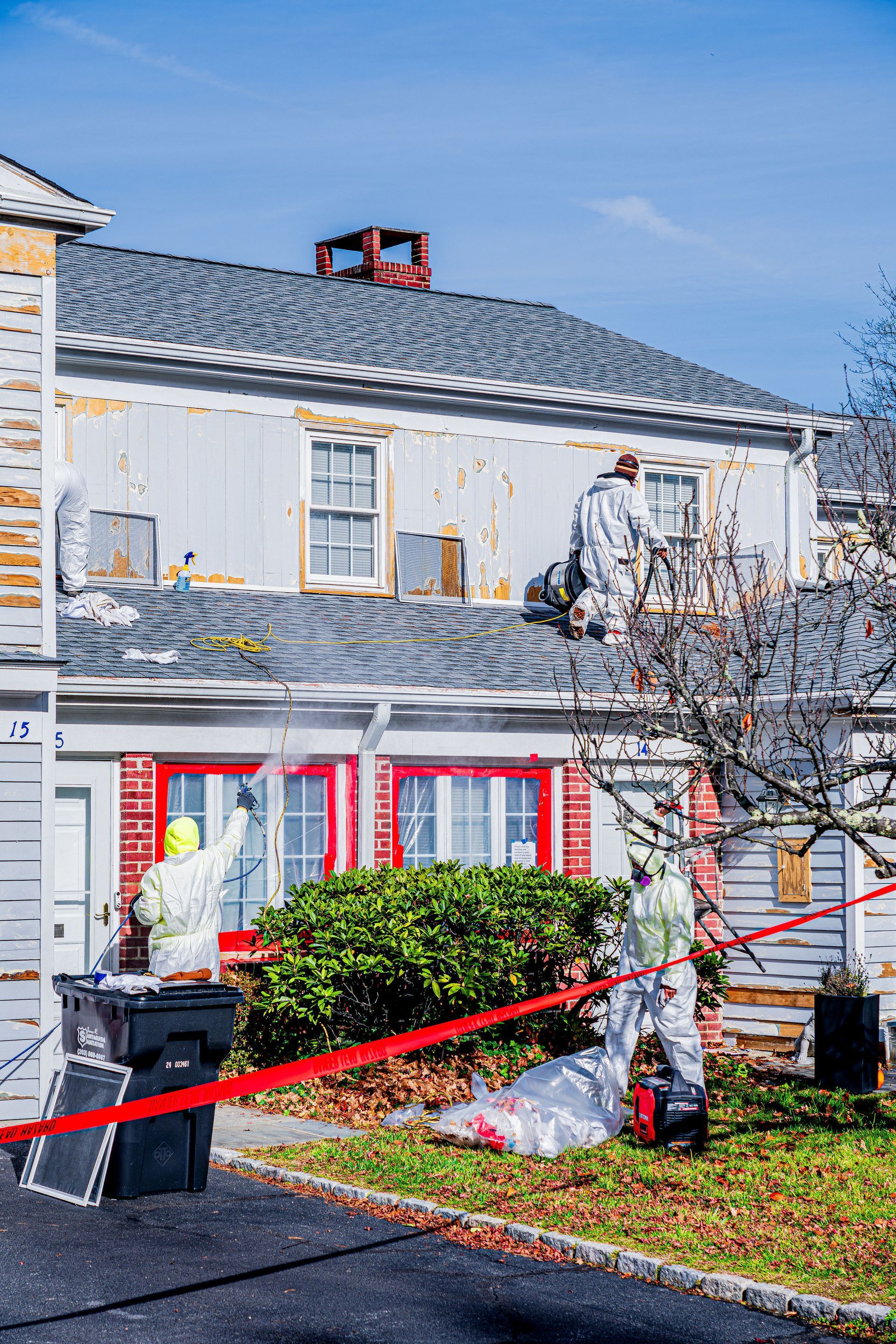 White house with red shutters, Halloween web decorations, and red caution tape across the front yard.