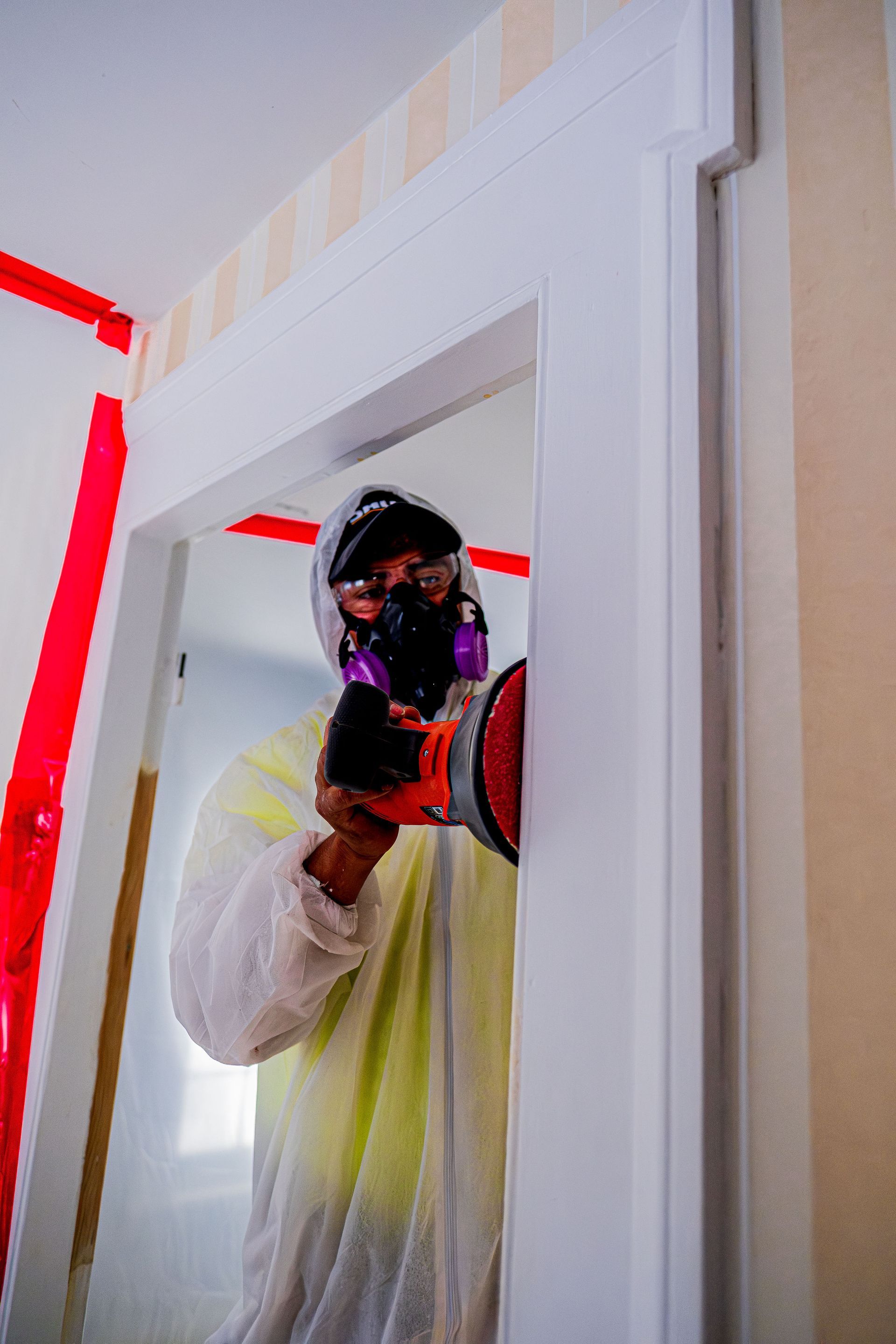 Person in white protective clothing and black face mask taking a mirror selfie in a doorway