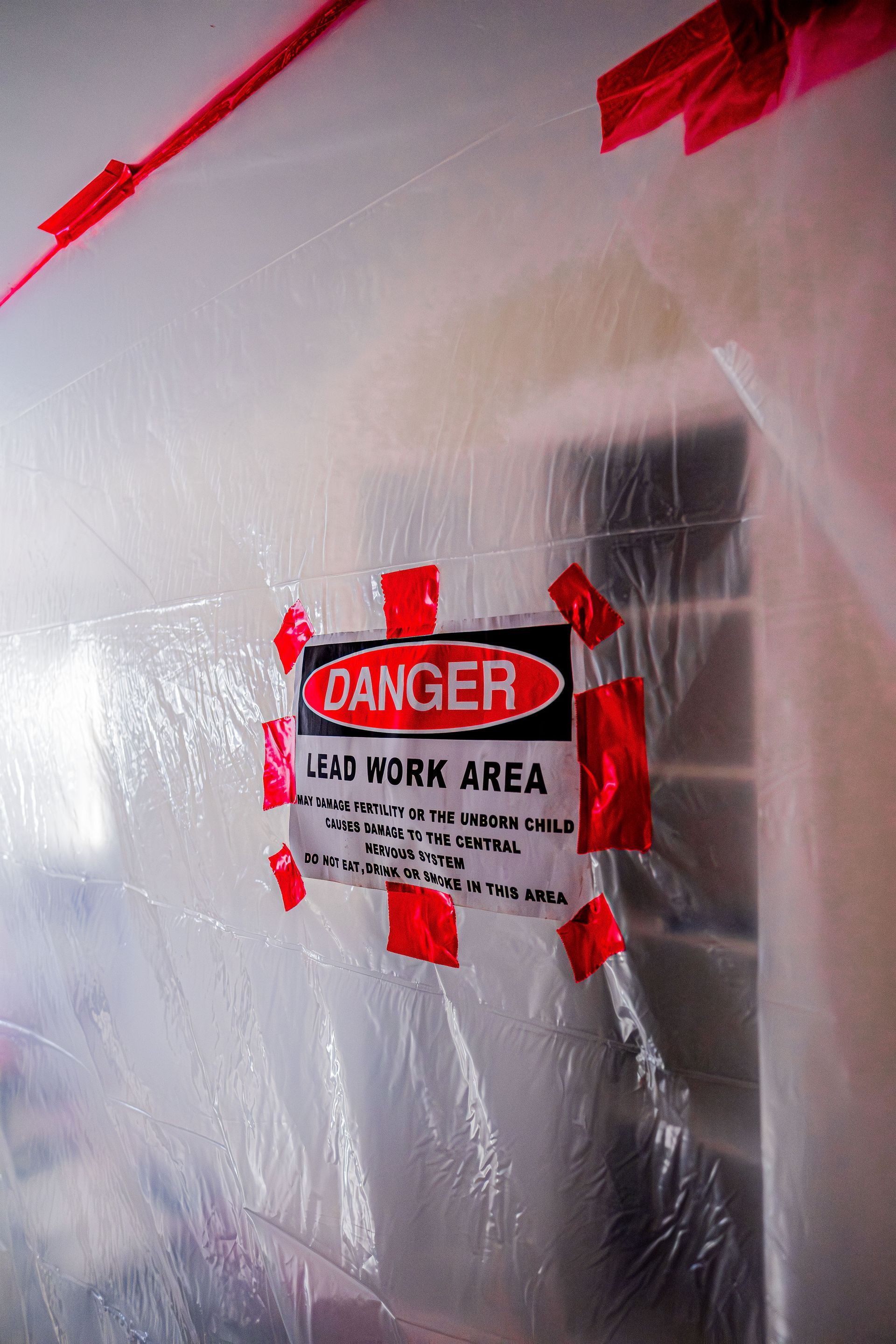 Caution sign on a plastic-covered wall marking a live work area during renovation
