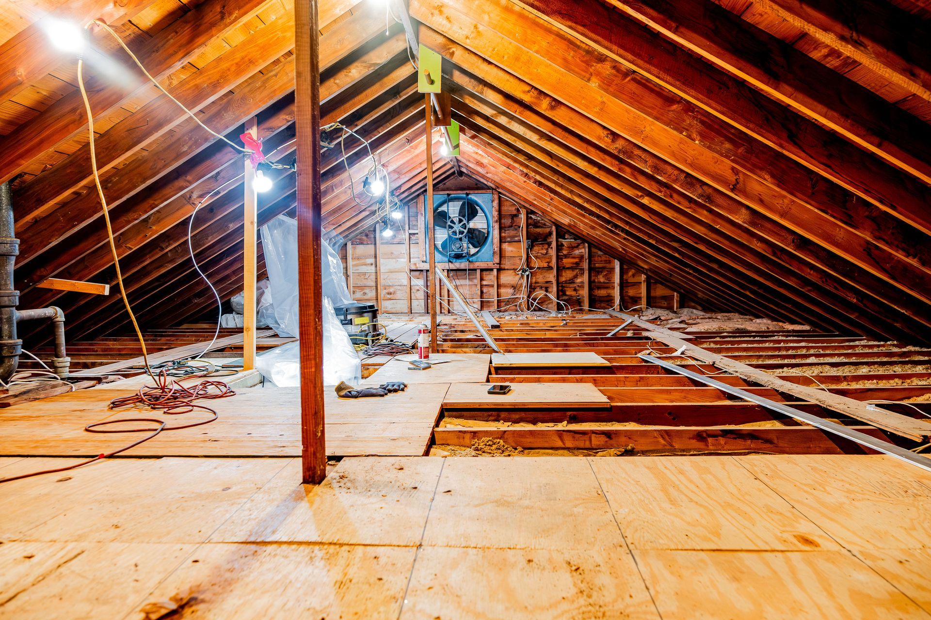 Attic under renovation with exposed beams, insulation, and unfinished wooden flooring and framing
