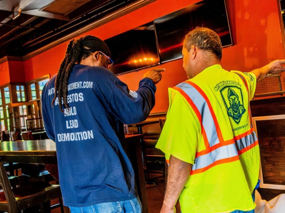Two men wearing safety vests are performing an asbestos inspection