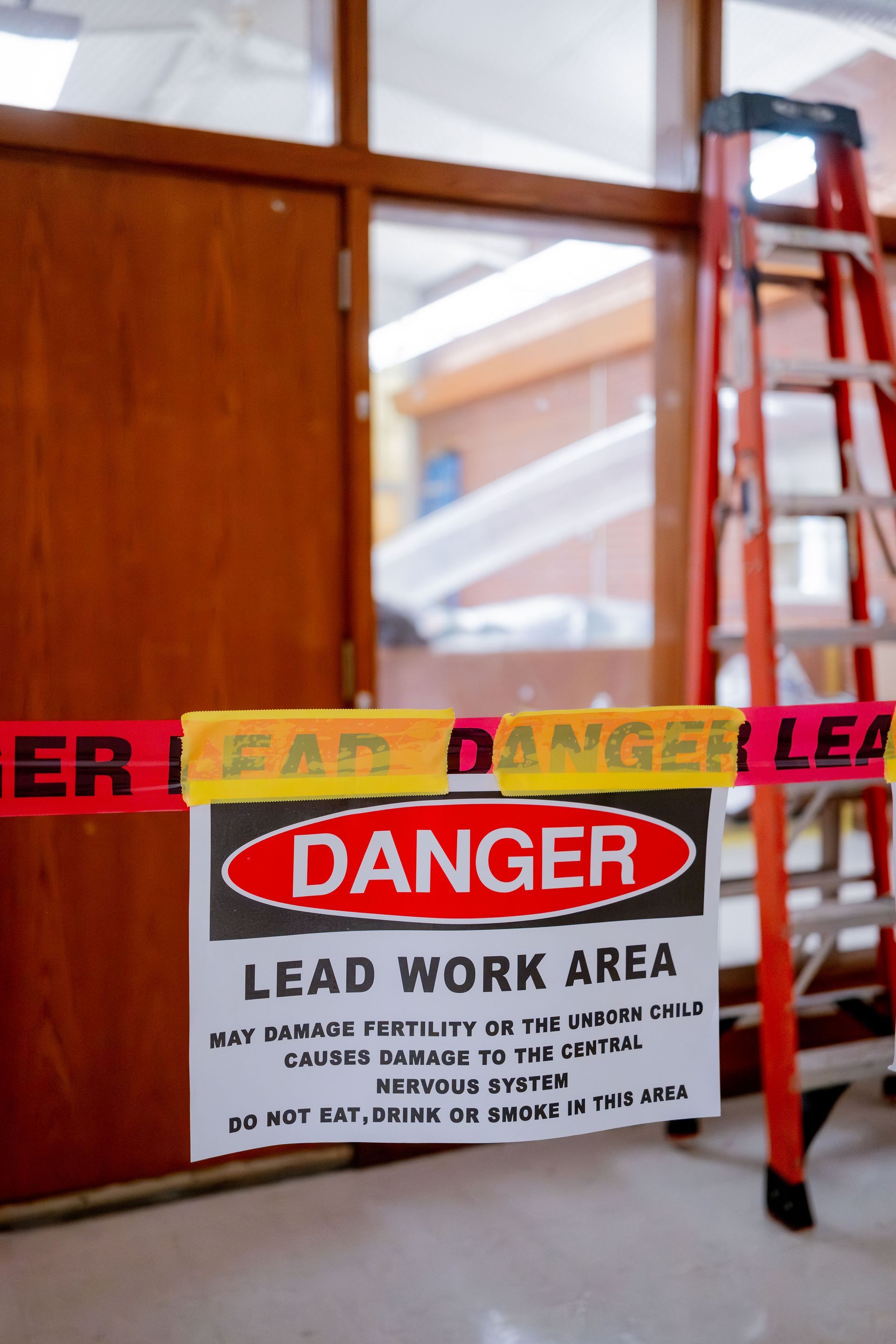 Danger sign in front of a taped-off ladder inside a building under construction.