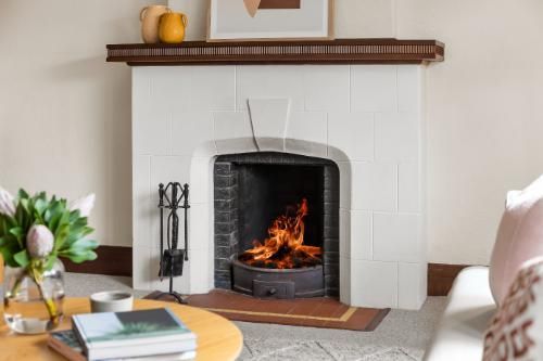 Elegant living room with a traditional fireplace featuring a clean white mantel and a mirror above, surrounded by cozy seating and natural light.