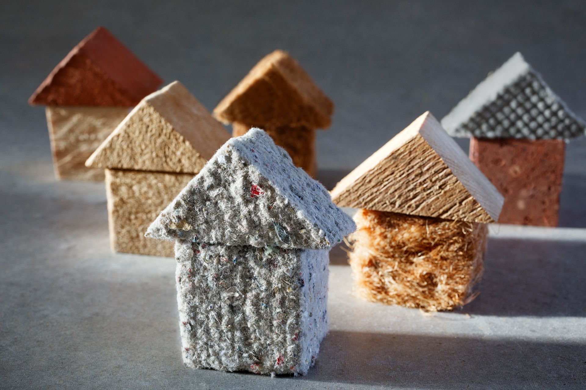 Small handmade house ornaments in muted colors arranged on a tabletop