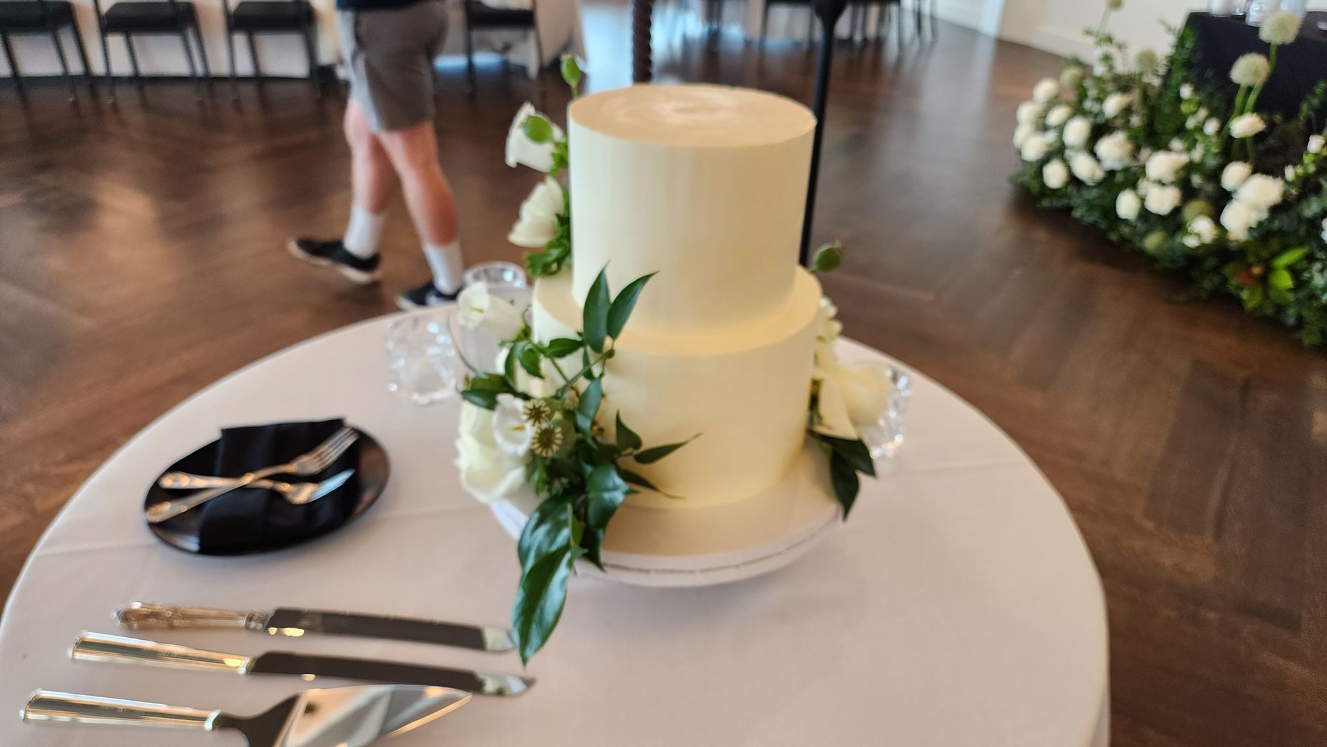 A wedding cake is sitting on a table with knives and forks.