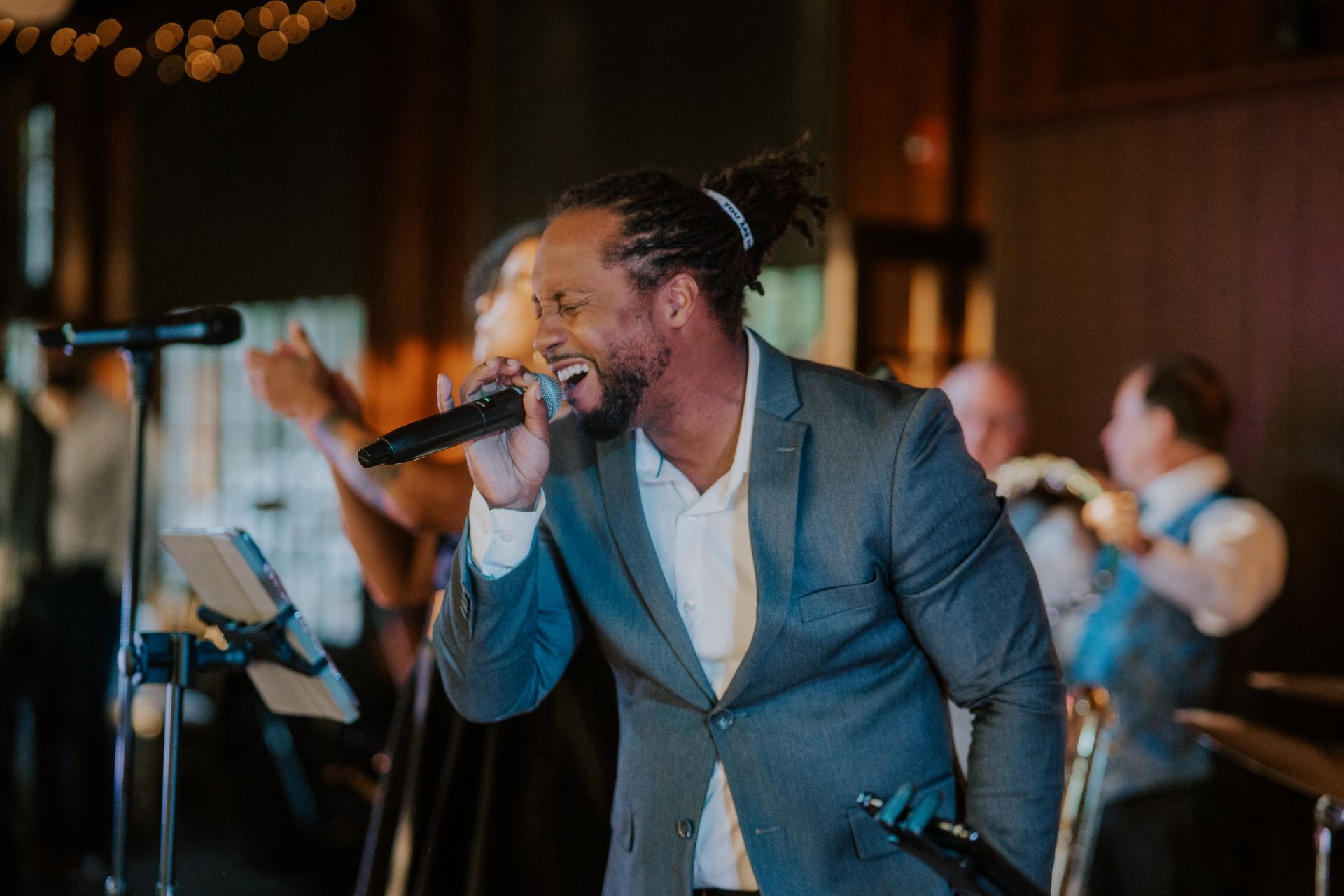 A man in a suit is singing into a microphone at a wedding reception.