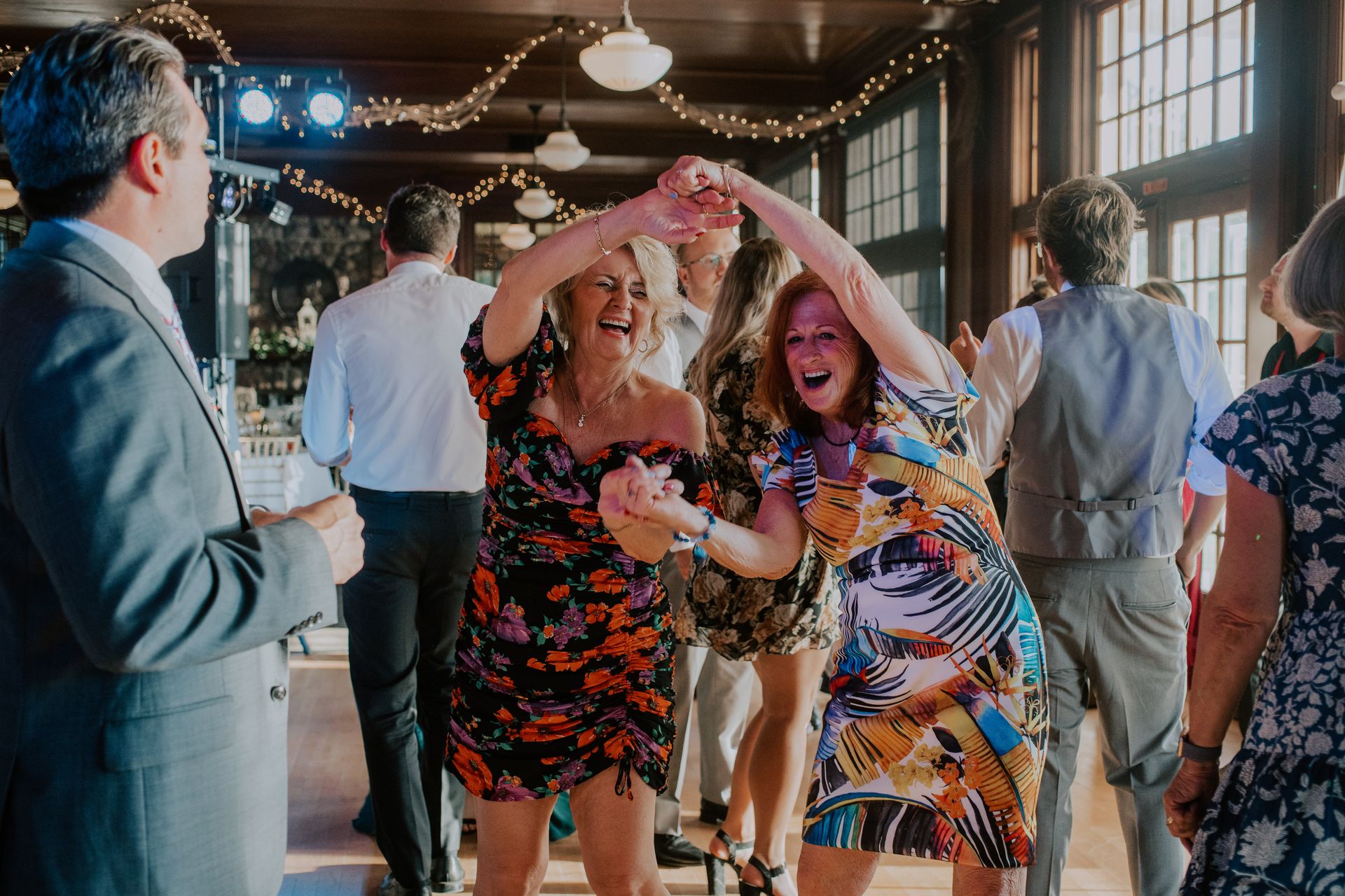 A group of people are dancing in a room at a wedding reception.