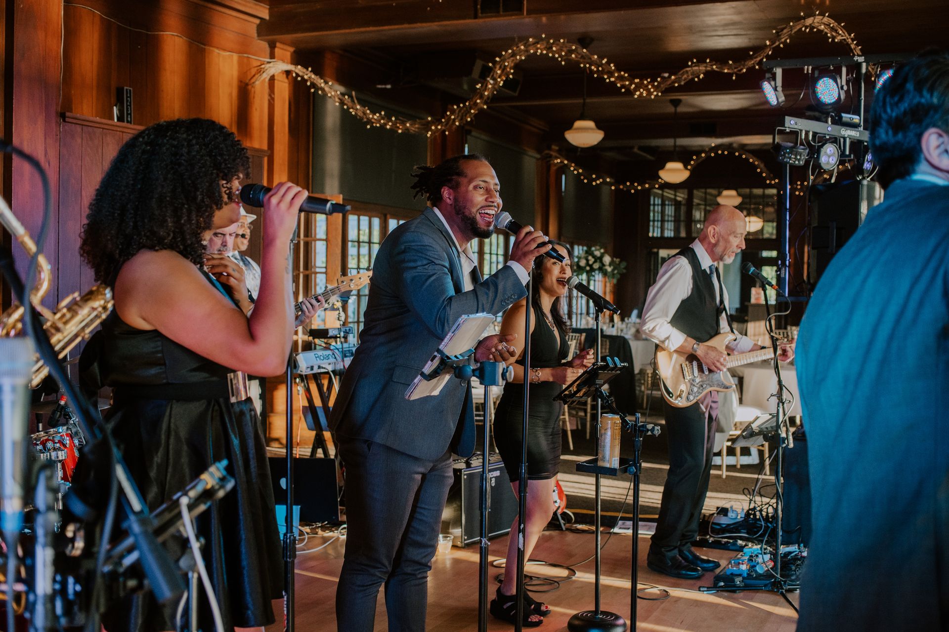 A group of people are playing instruments and singing into microphones on a stage.