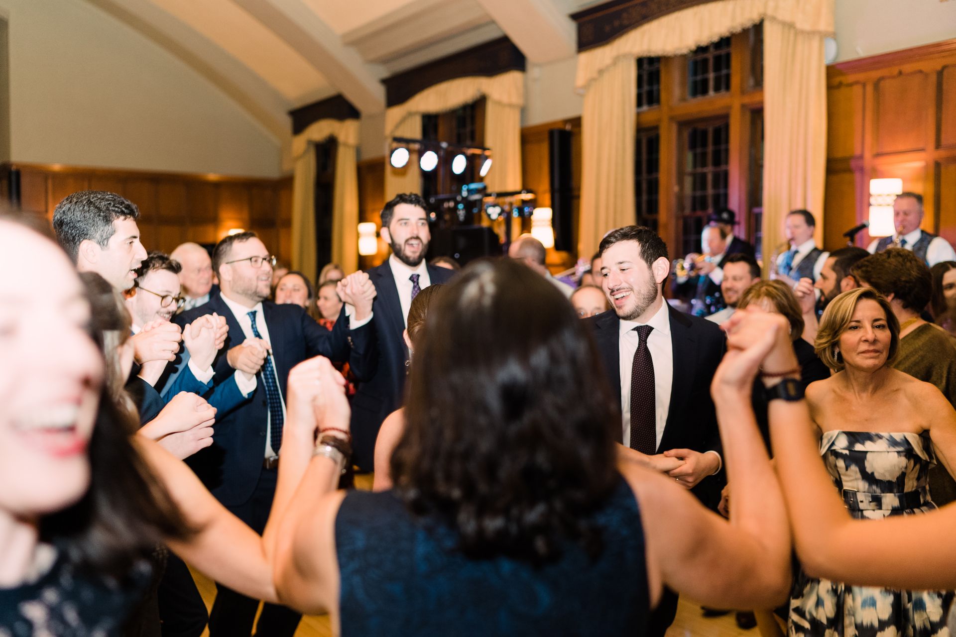 A group of people are dancing in a room at a wedding reception.
