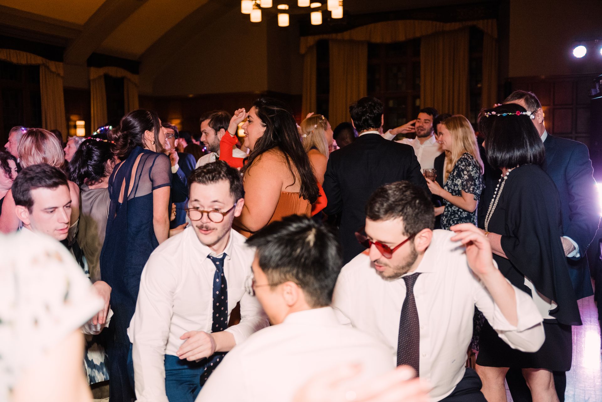 A group of people are dancing in a room at a wedding reception.