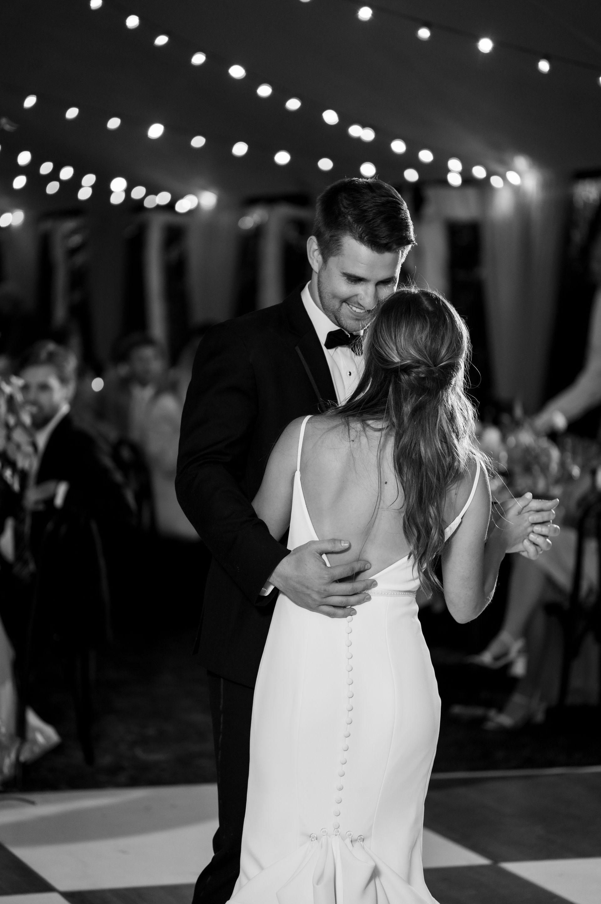A bride and groom are dancing on a checkered dance floor.