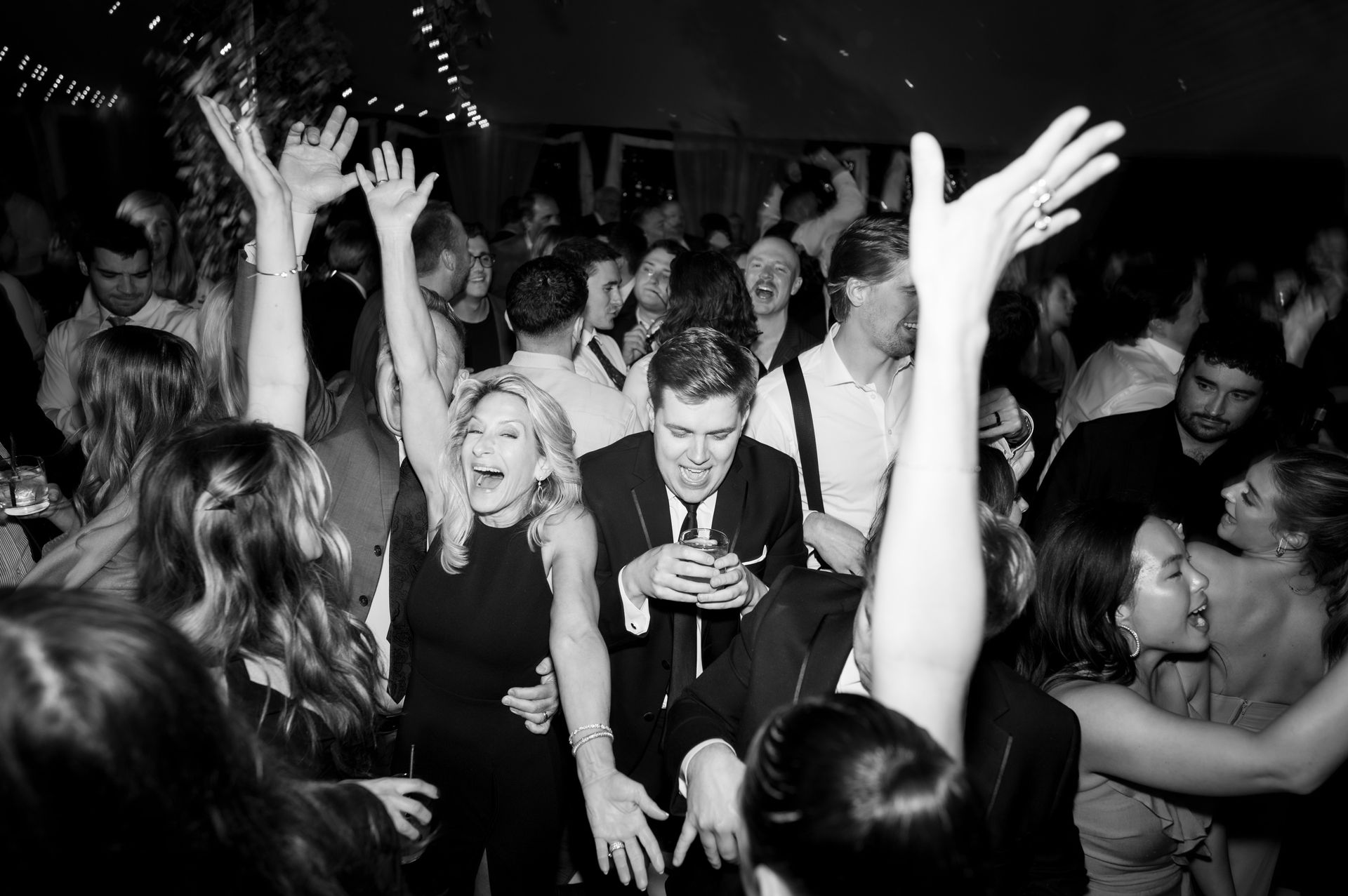A black and white photo of a crowd of people dancing at a party.