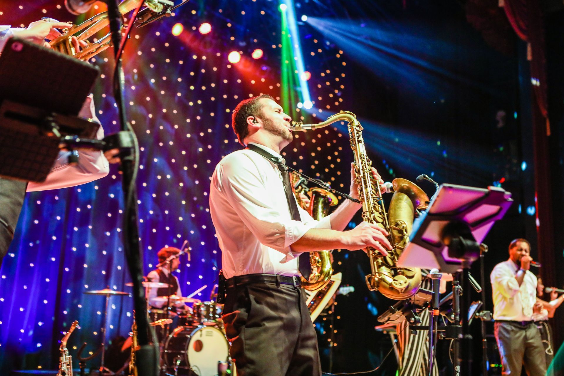 a man playing a saxophone on a stage with other musicians from Main Street Soul.