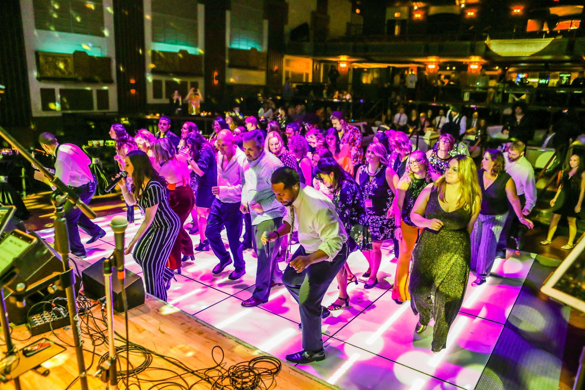 a large group of people are dancing on a dance floor at a party .
