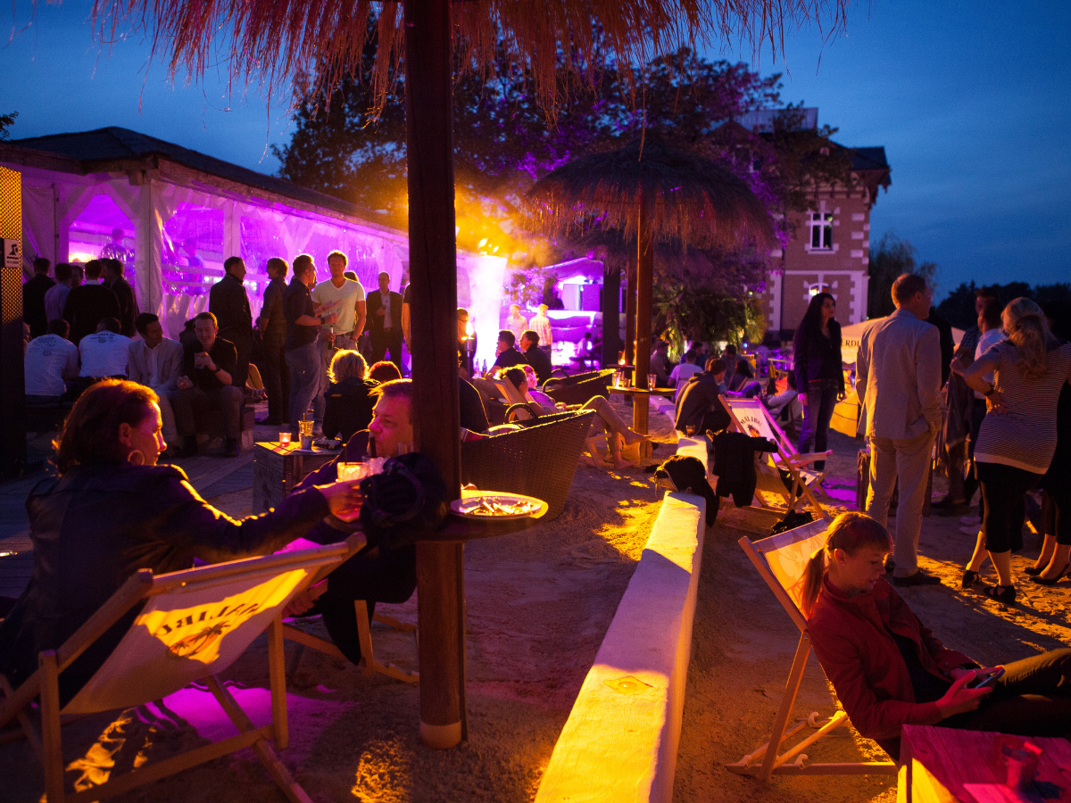 a group of people are sitting in chairs under an umbrella at a party .