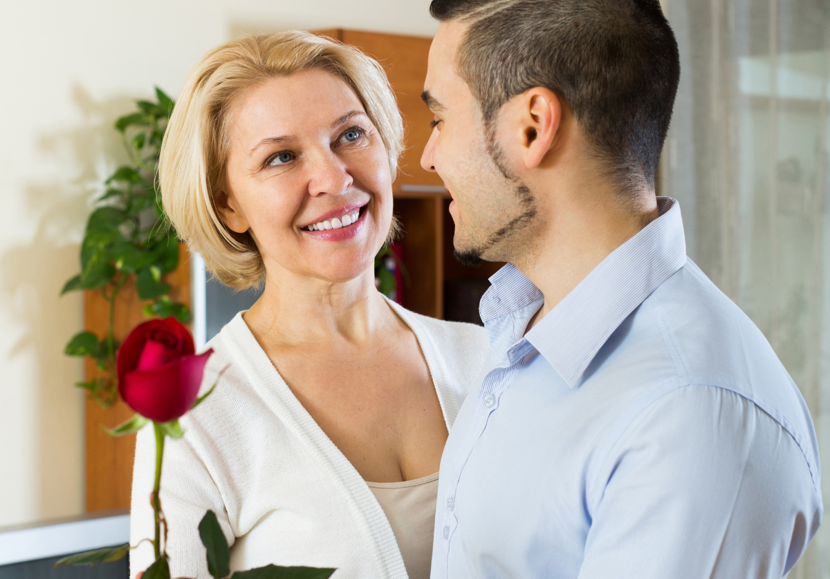 a son is giving his mom a rose and they are looking at each other .