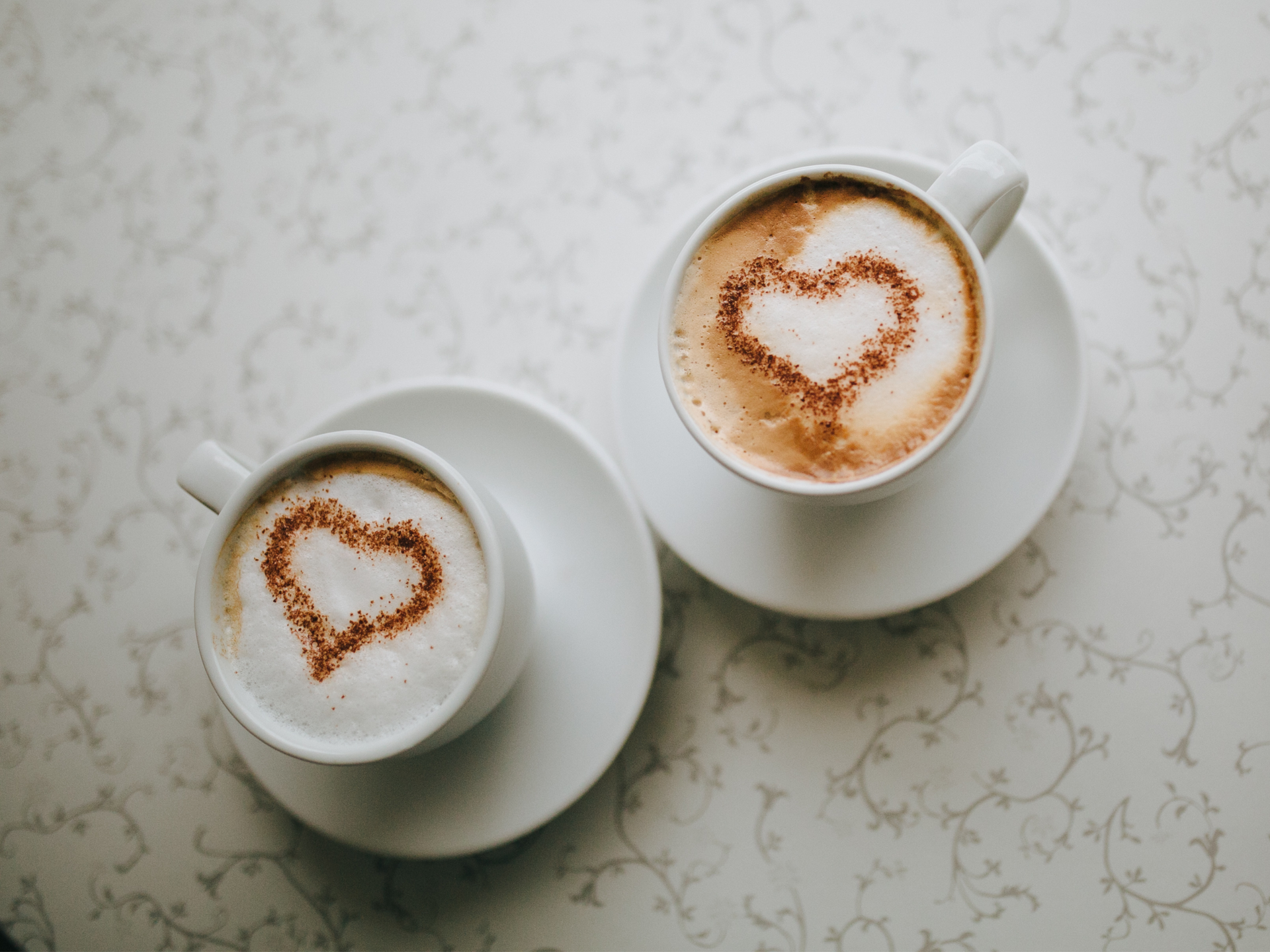 two cups of coffee with hearts drawn on the foam from an elegant wedding barista
