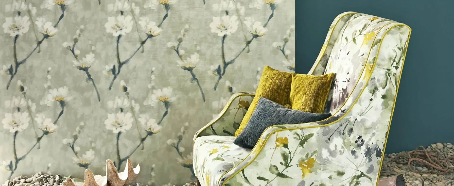 Blomstertapet bag en mønstret lænestol med gule og grå puder