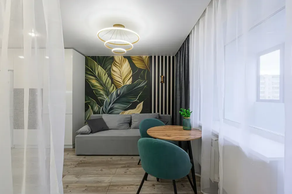 Lille opholdsstue med sofa, spisebord og botanisk tapet.