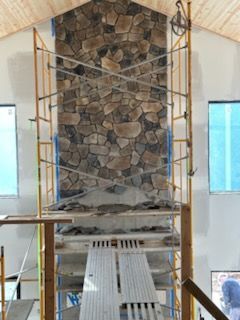 Scaffolding around a stone wall under construction in a bright interior room