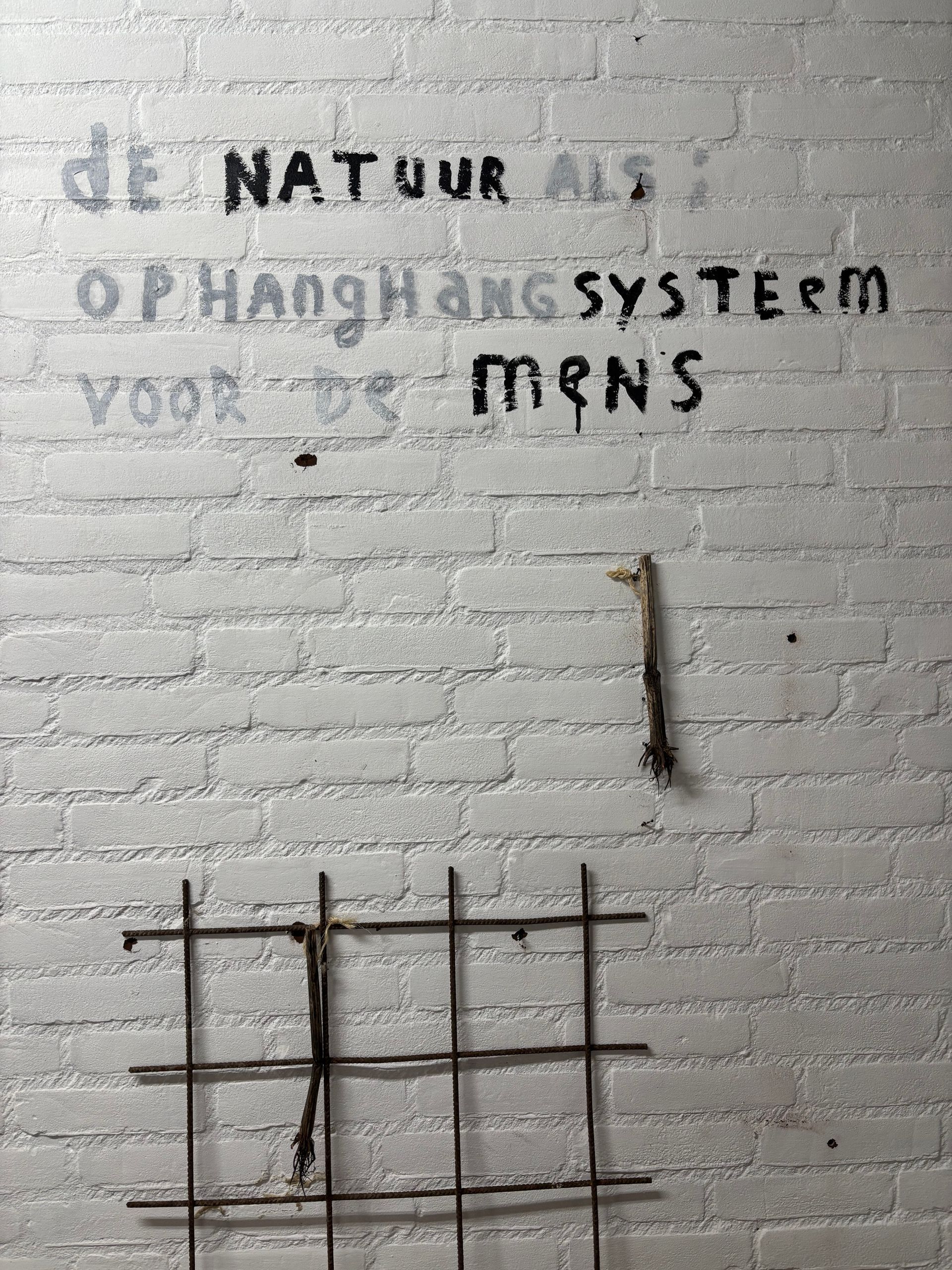 White brick wall with handwritten Dutch text: 