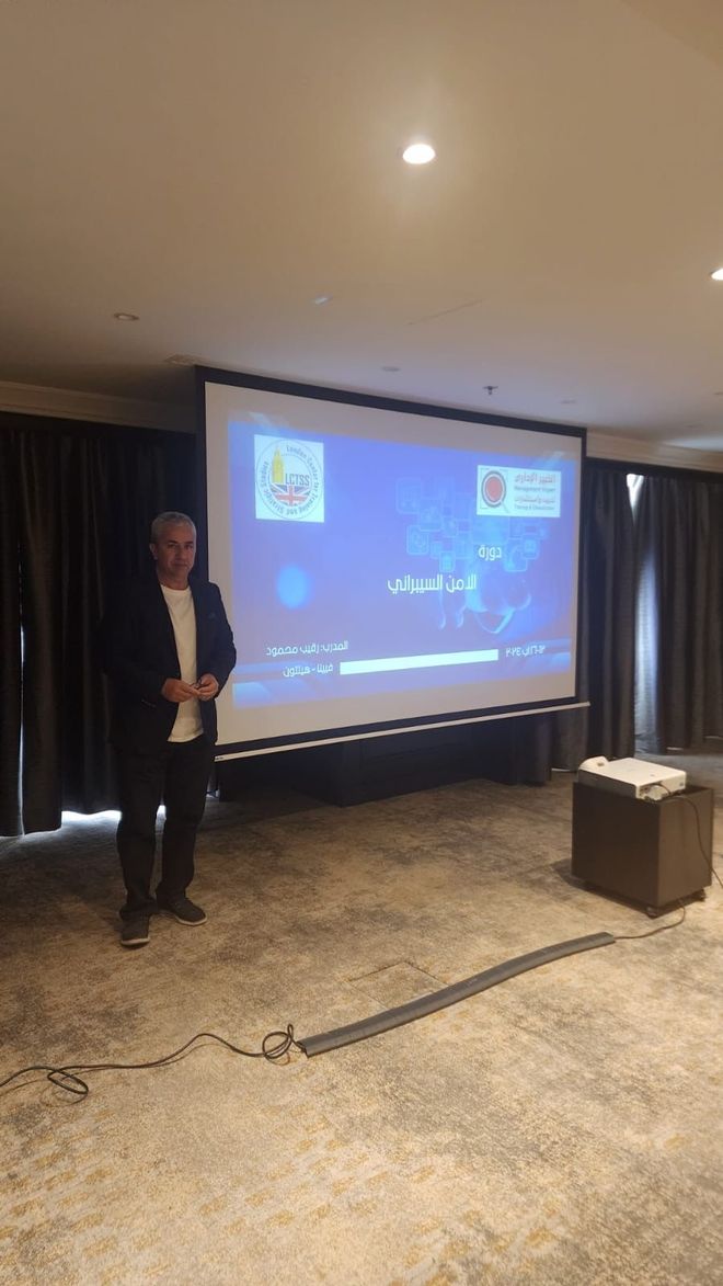A man is standing in front of a large screen in a room.