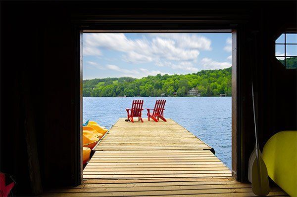 Two red chairs are sitting on a dock overlooking a lake.