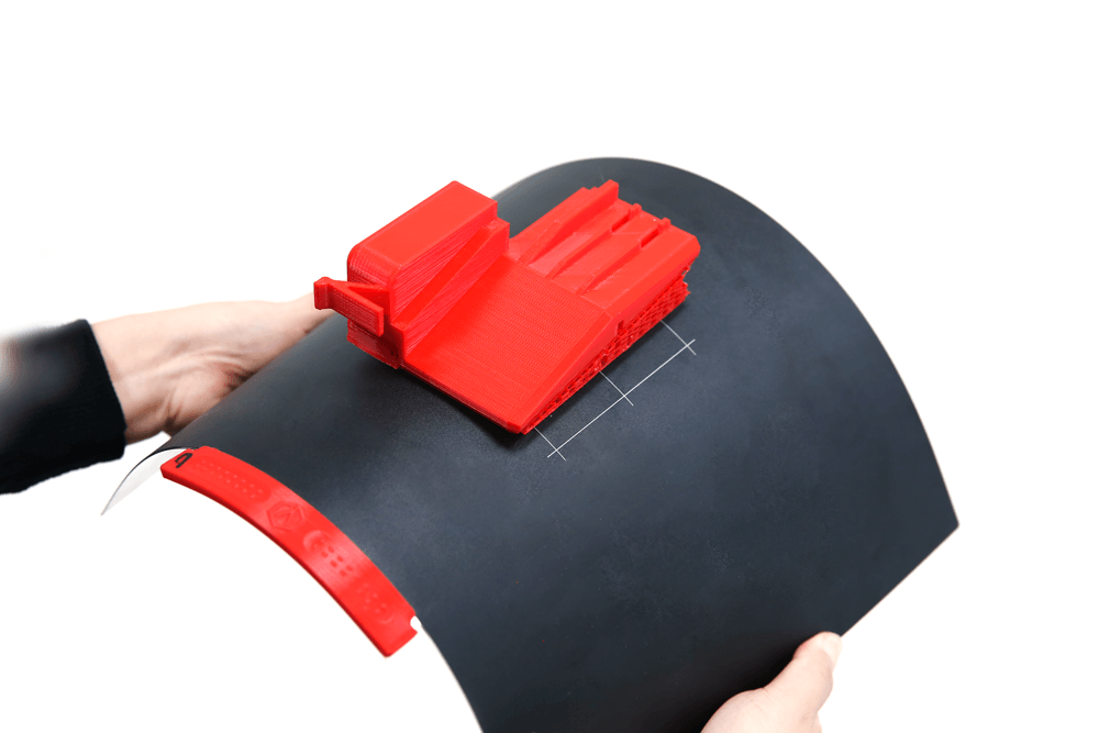 Een persoon houdt een stuk zwart papier vast met daarop een rood voorwerp.