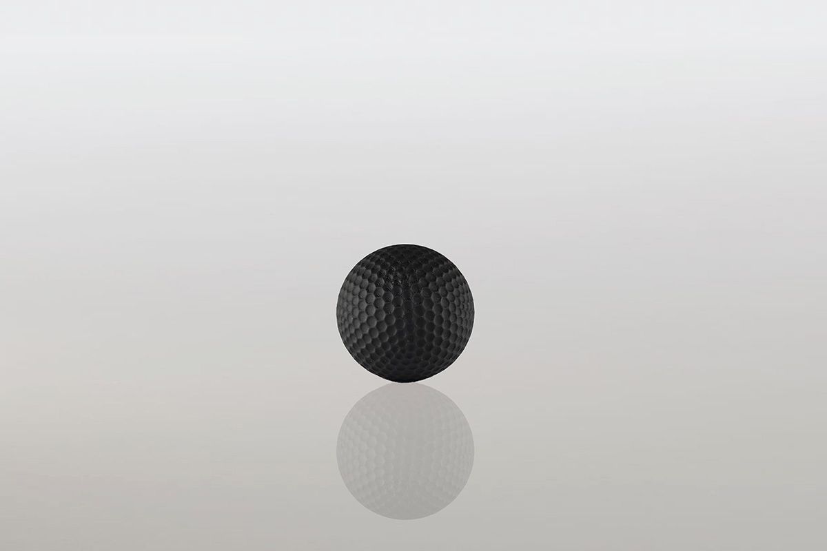 Een zwarte golfbal ligt op een wit oppervlak.