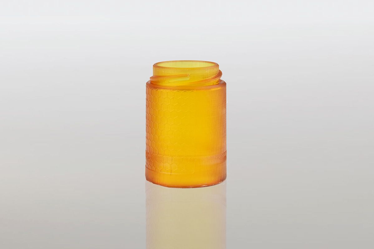 Een gele glazen fles staat op een wit oppervlak.