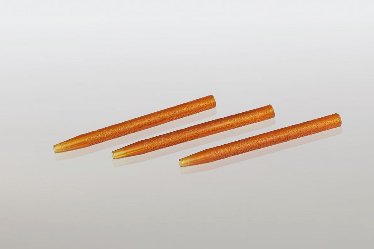 Drie oranje tandenstokers liggen op een wit oppervlak.