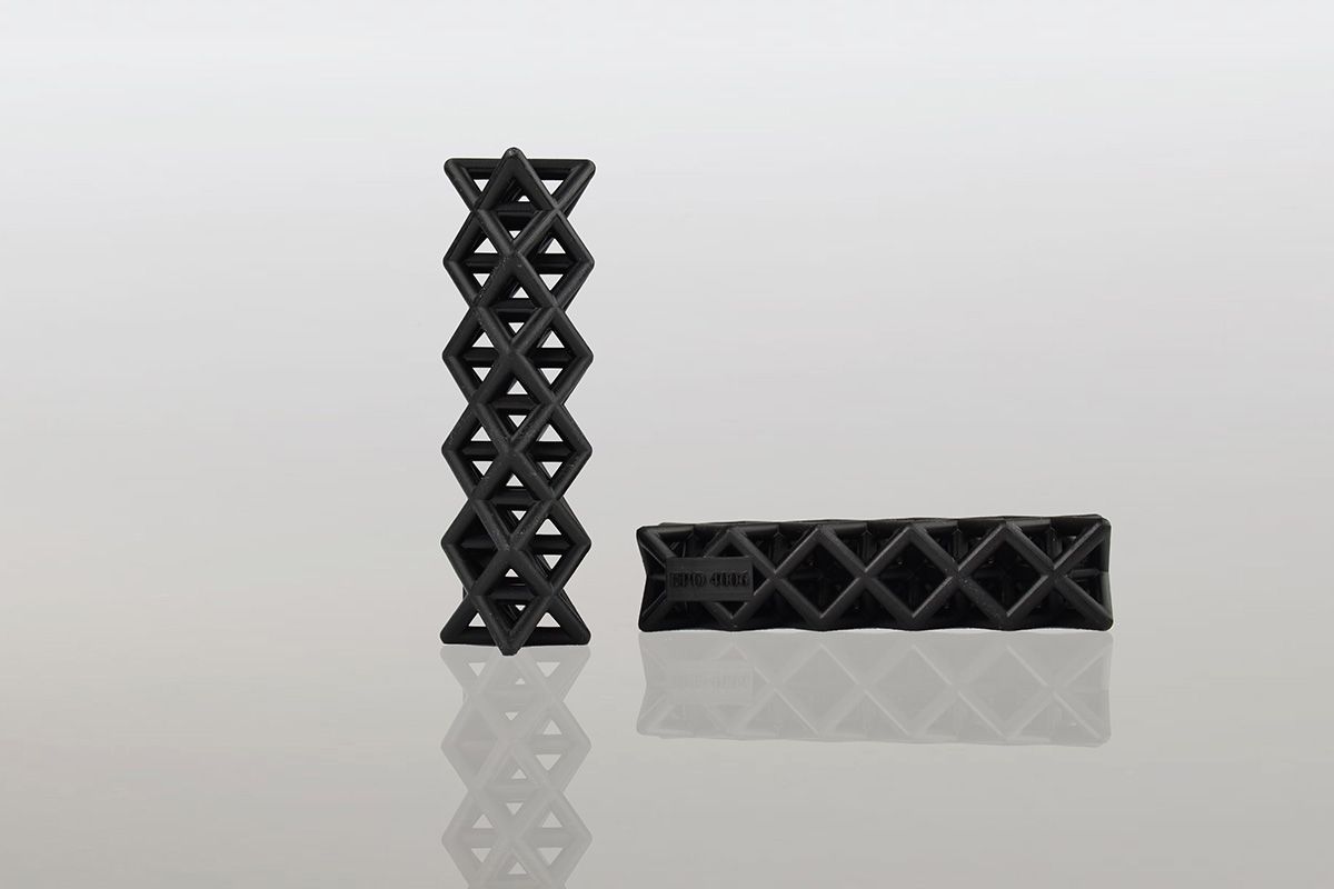Twee zwarte geometrische objecten liggen op een wit oppervlak.