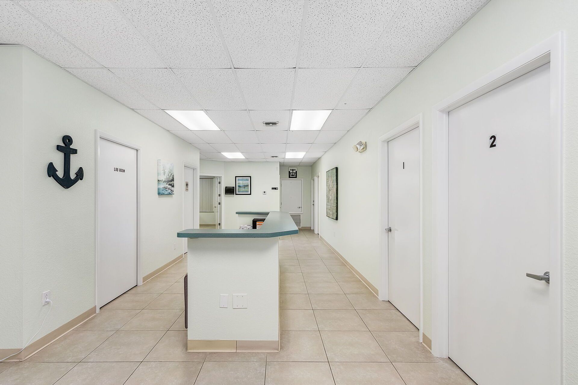 Empty white hallway with doors and a central counter in a bright office or clinic