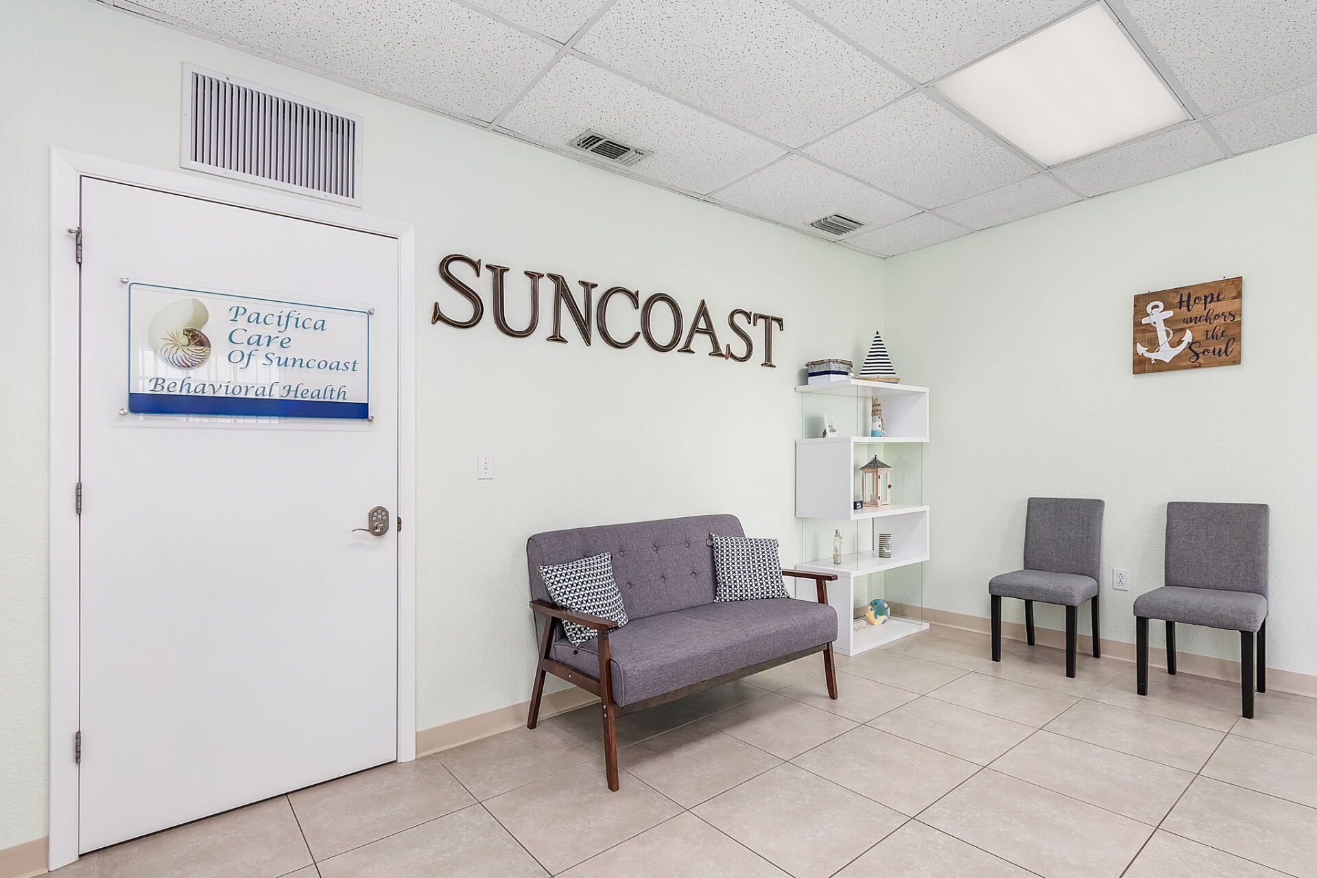 Suncoast waiting room with chairs, sofa, wall shelves, and tiled floor