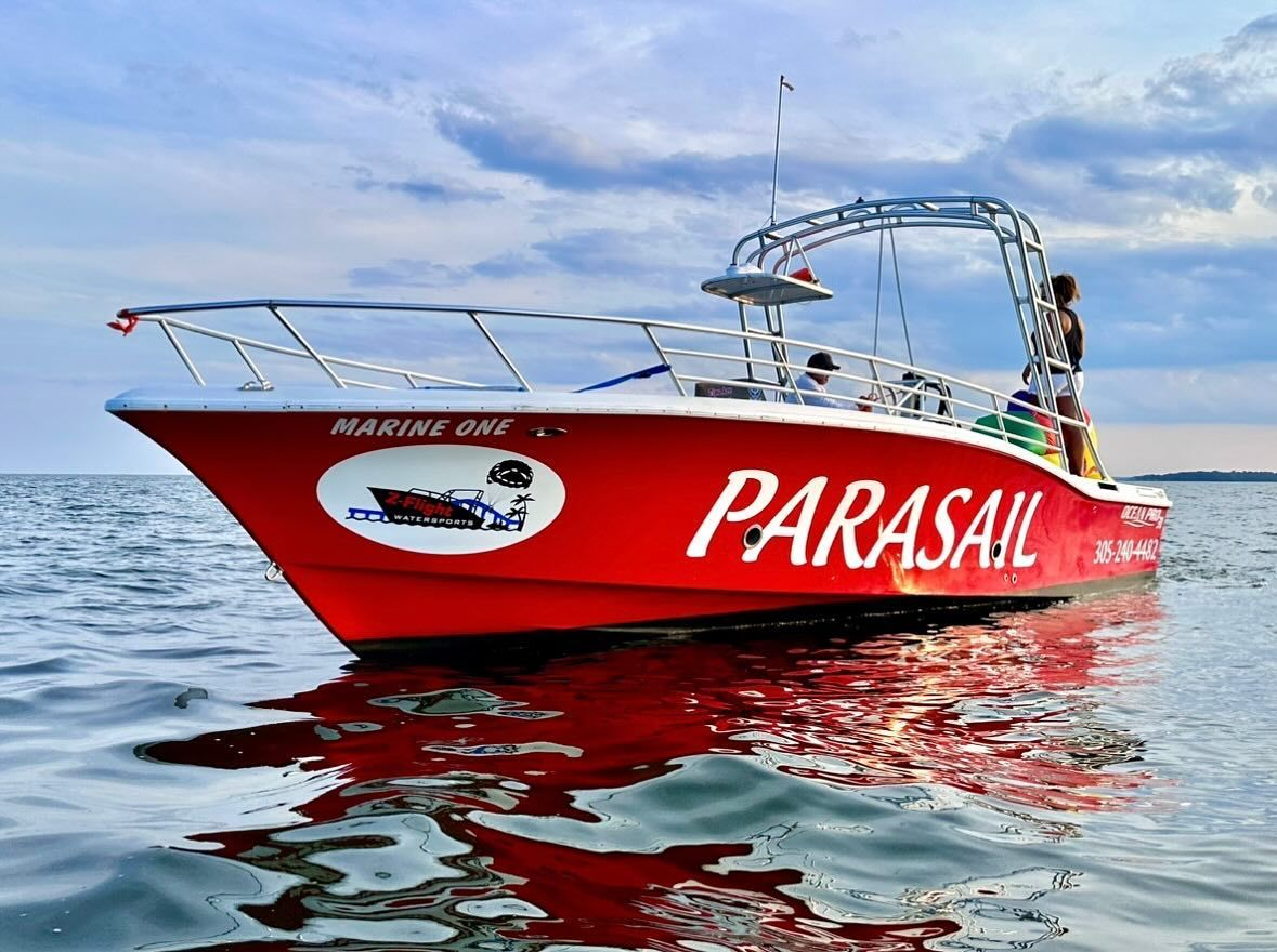 A red parasail boat is floating on top of a body of water