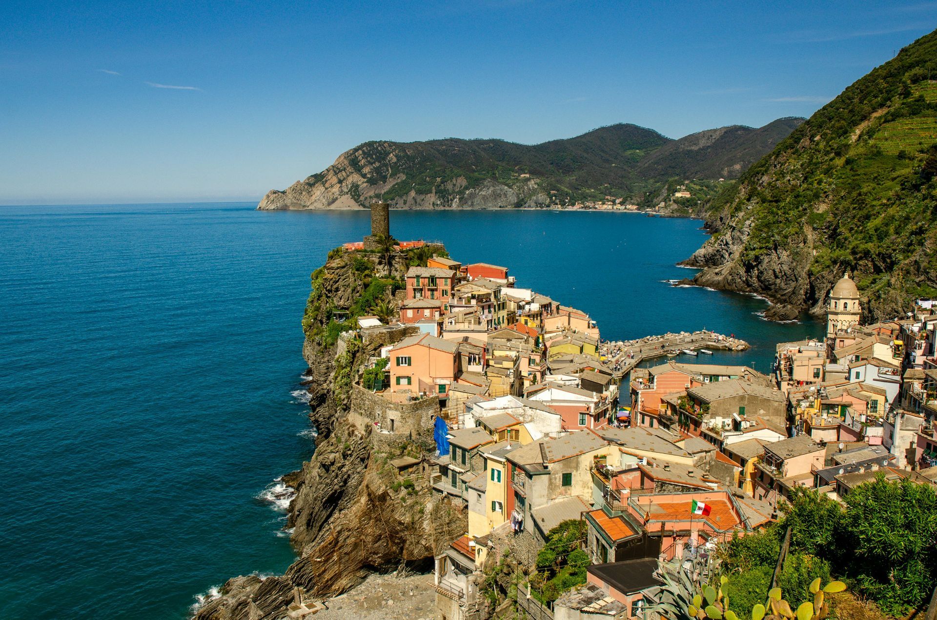 Coastal Italian village, colorful buildings nestled on cliffs overlooking turquoise sea.