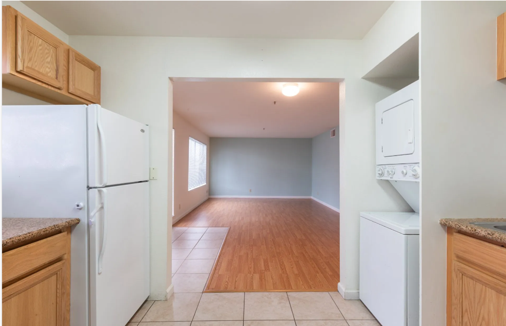 Photo showing a large living room the background and a kitchen in the foreground, with a space for a washer and dryer