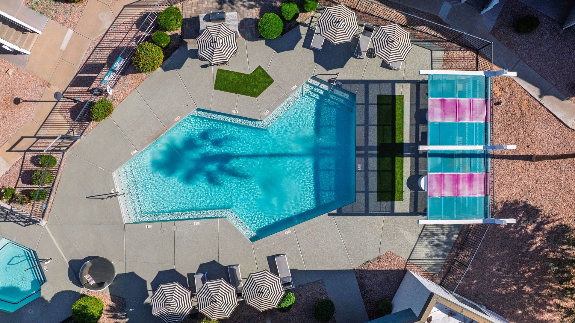 Aerial view of a turquoise pool surrounded by seating areas and landscaping.