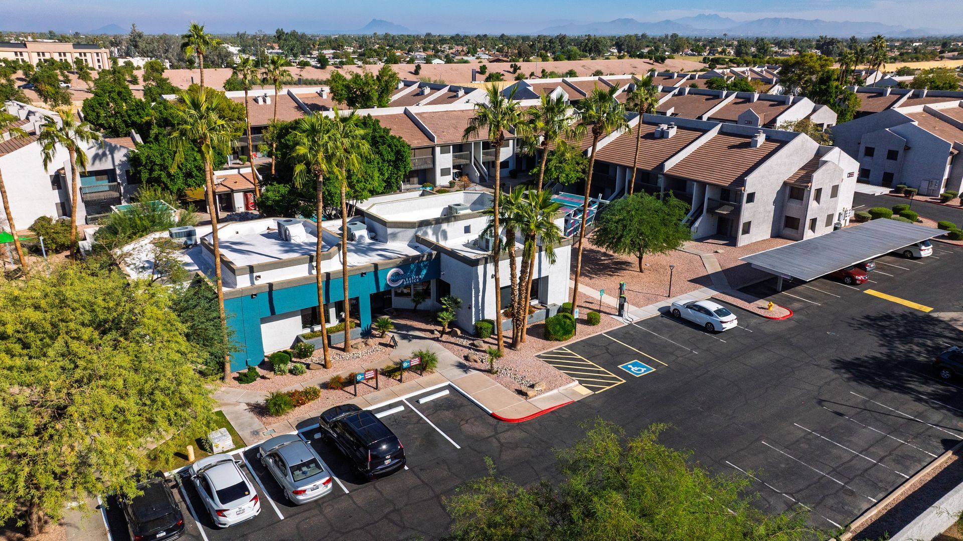 Apartment complex with palm trees, blue accent building, and parked cars in Arizona.