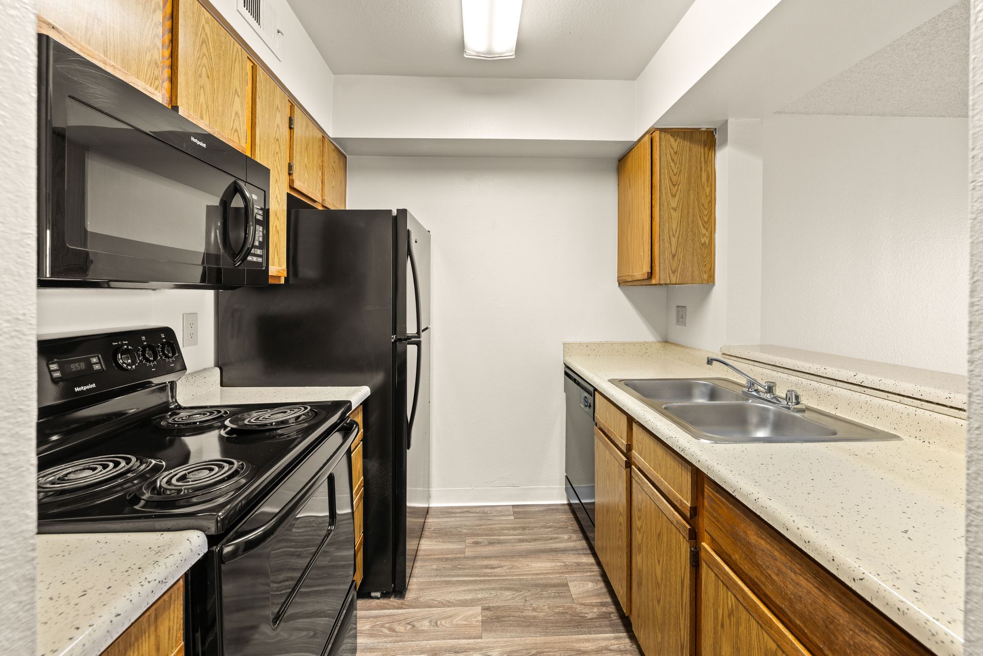 Kitchen with black appliances, wooden cabinets, and a sink.