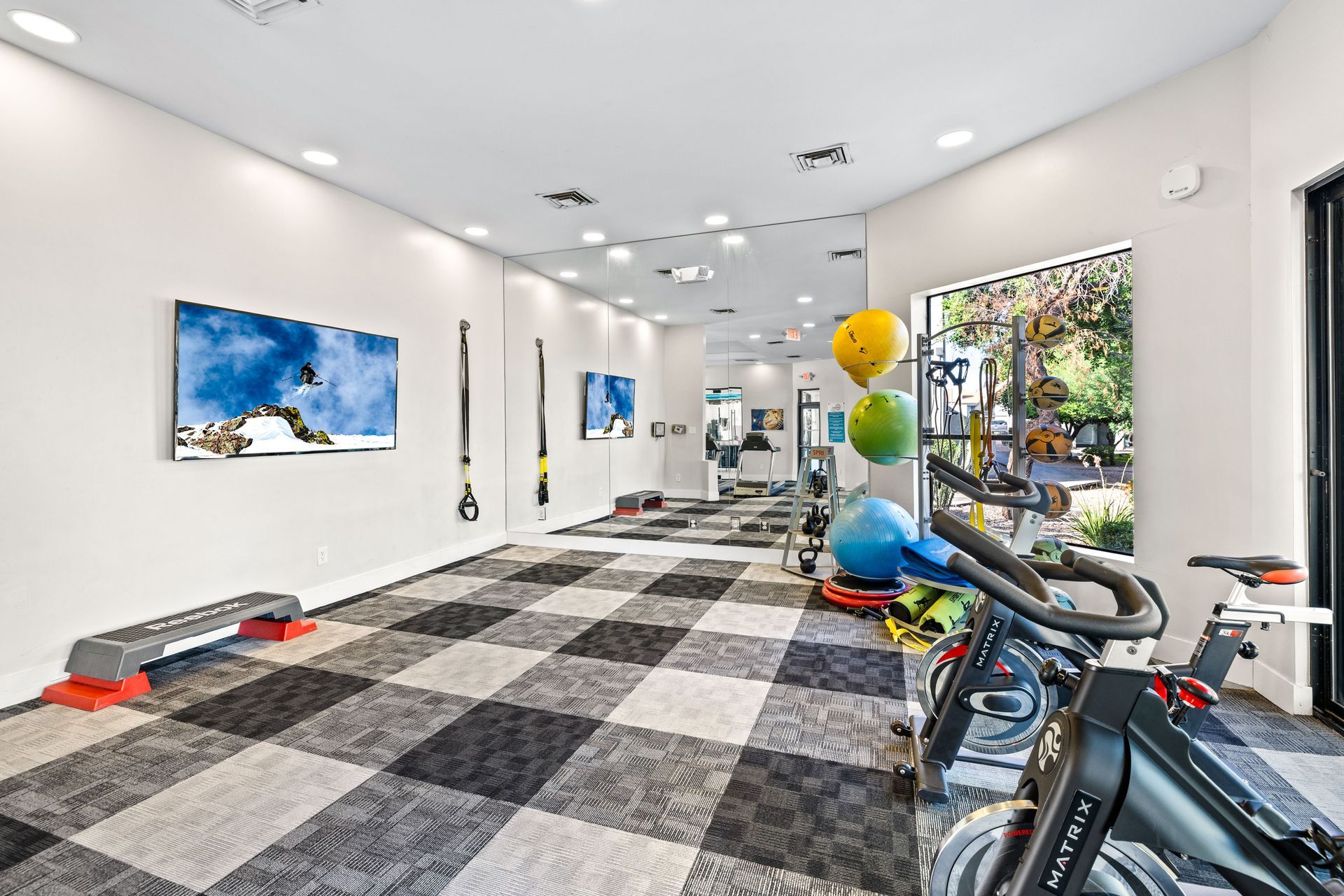 Gym interior with checkered floor, exercise equipment, and artwork on the walls.