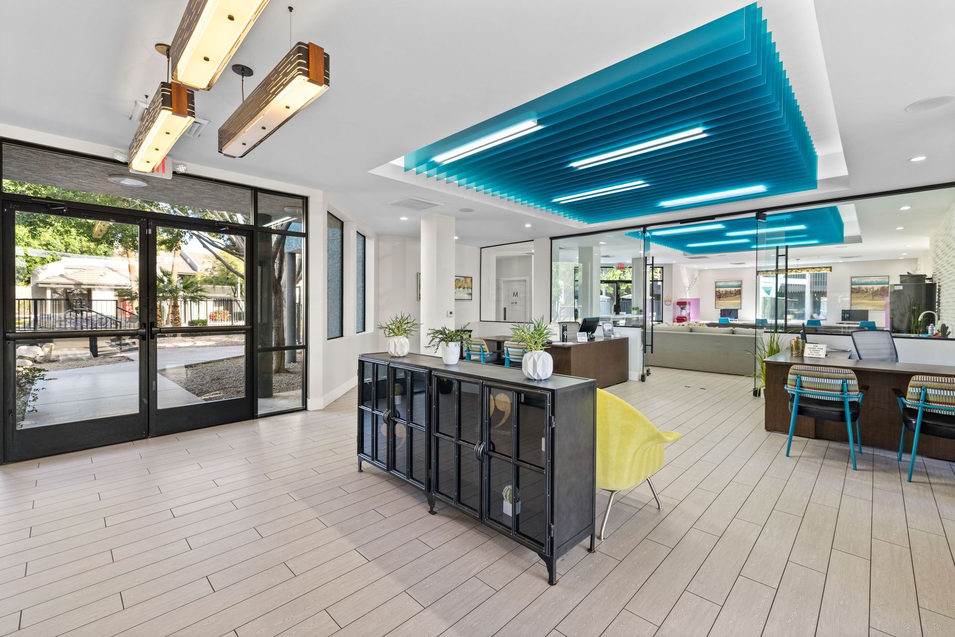 Bright office lobby with black cabinets, white floor, turquoise ceiling detail, and glass doors.