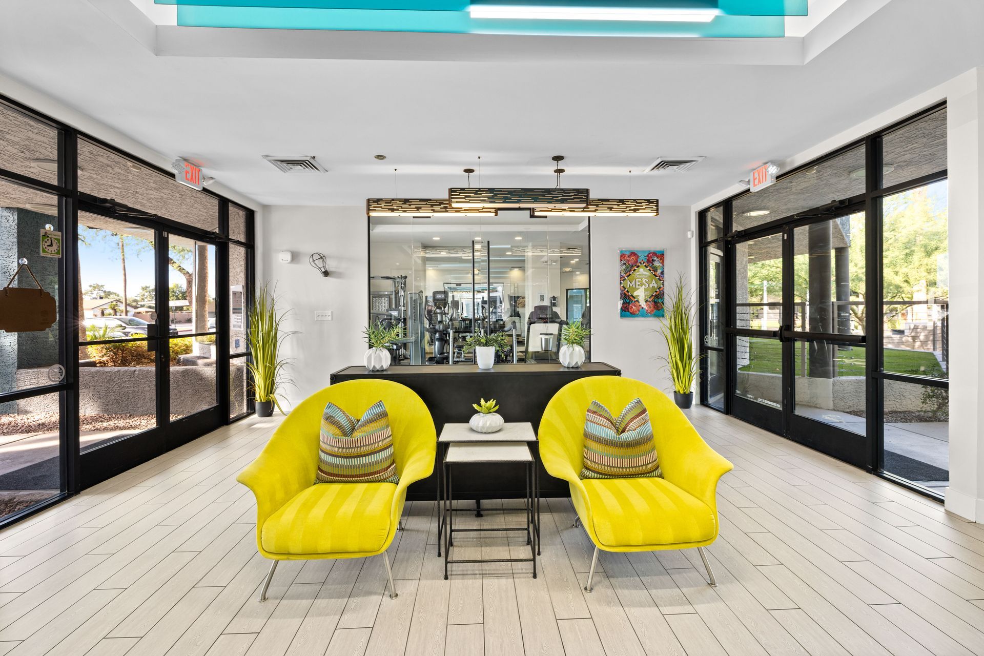 Yellow armchairs in a modern lobby with view of the gym through glass doors.