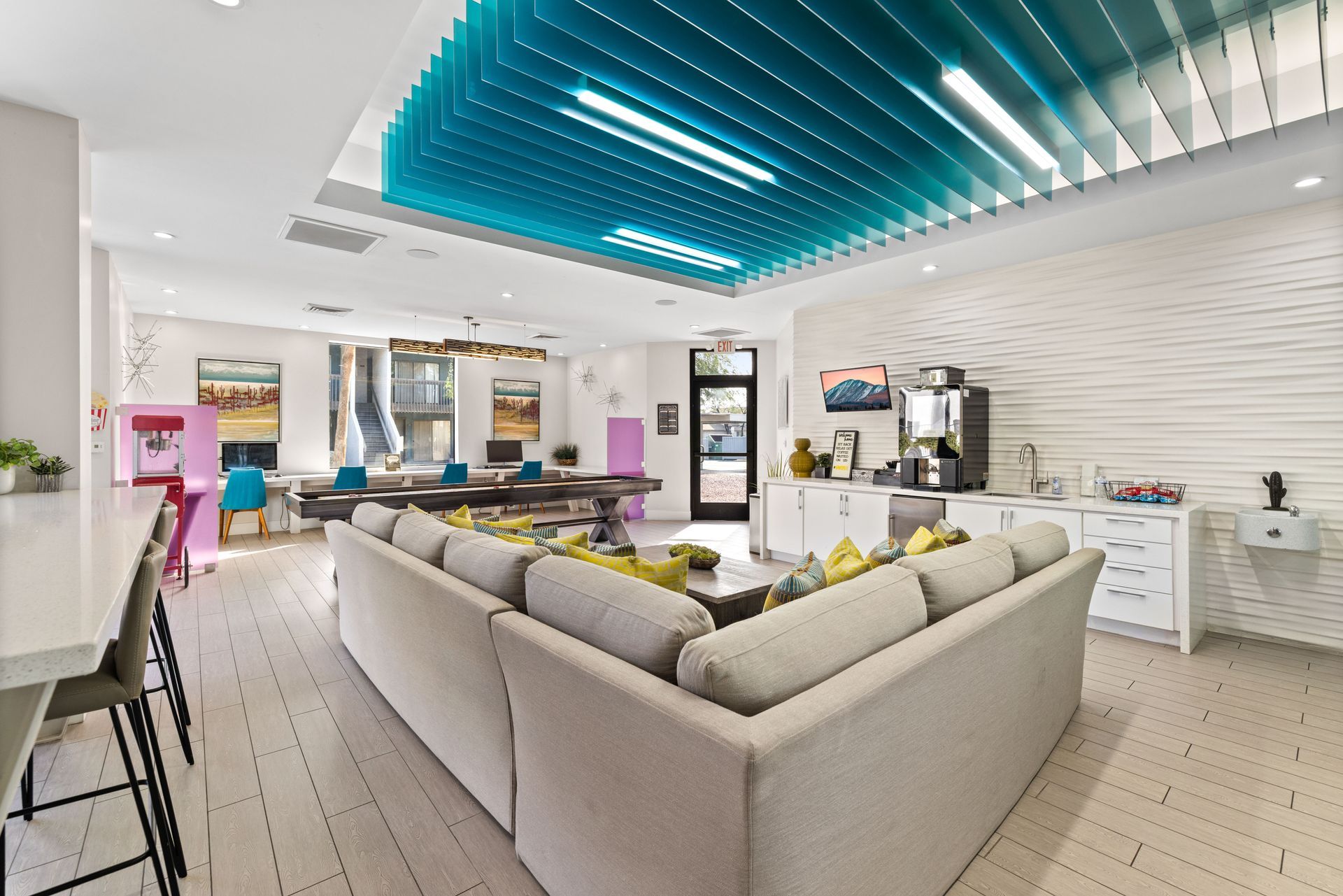 Modern lounge with a large gray sectional sofa, white and blue ceiling, and white walls at the Maddox.