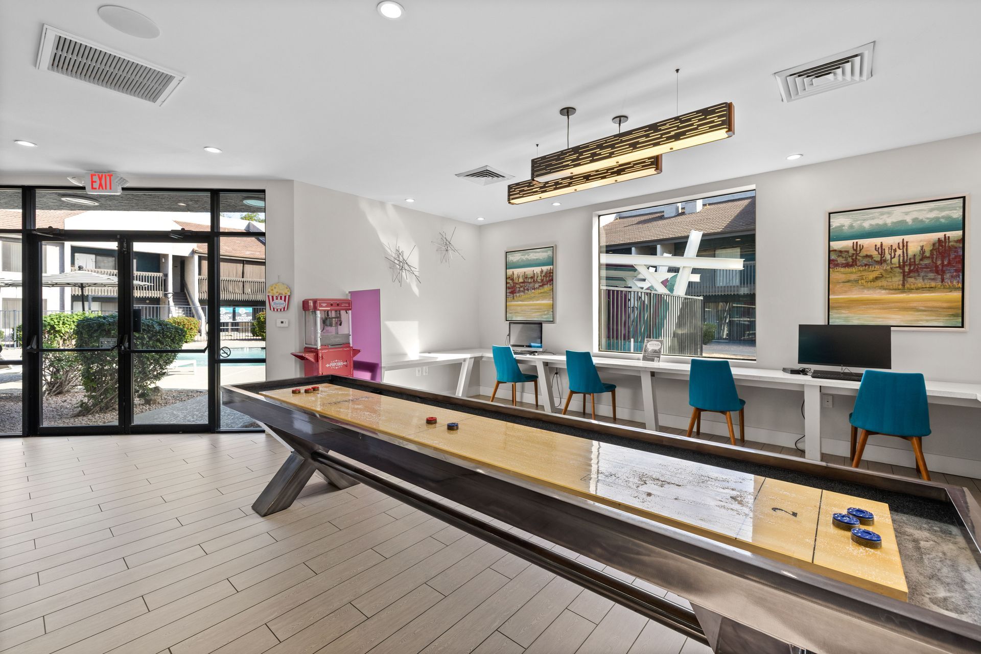 A community game room with a shuffleboard, computers, and a children's play area.