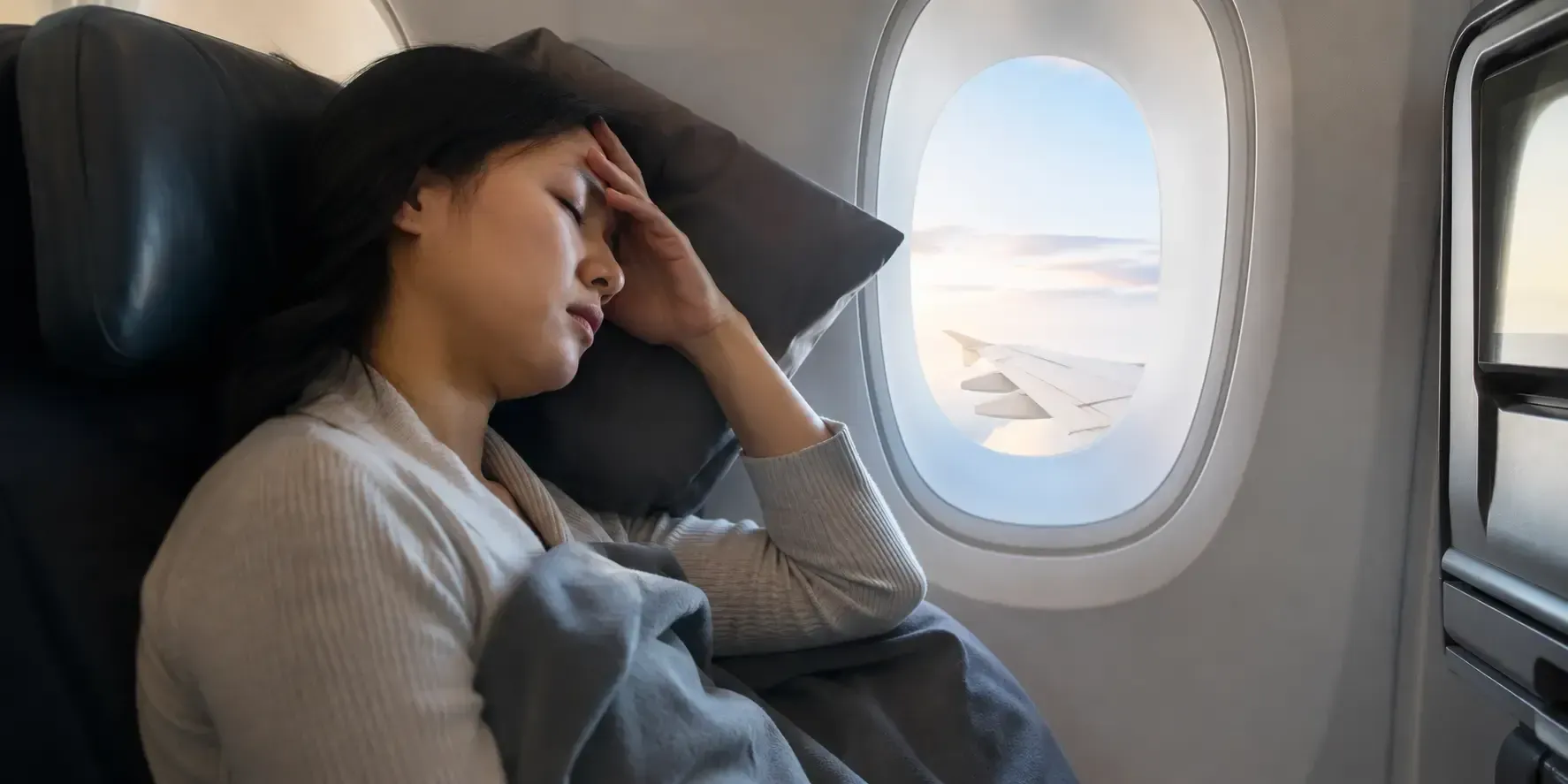 Tired traveler sleeping on an airplane during a long flight across time zones.