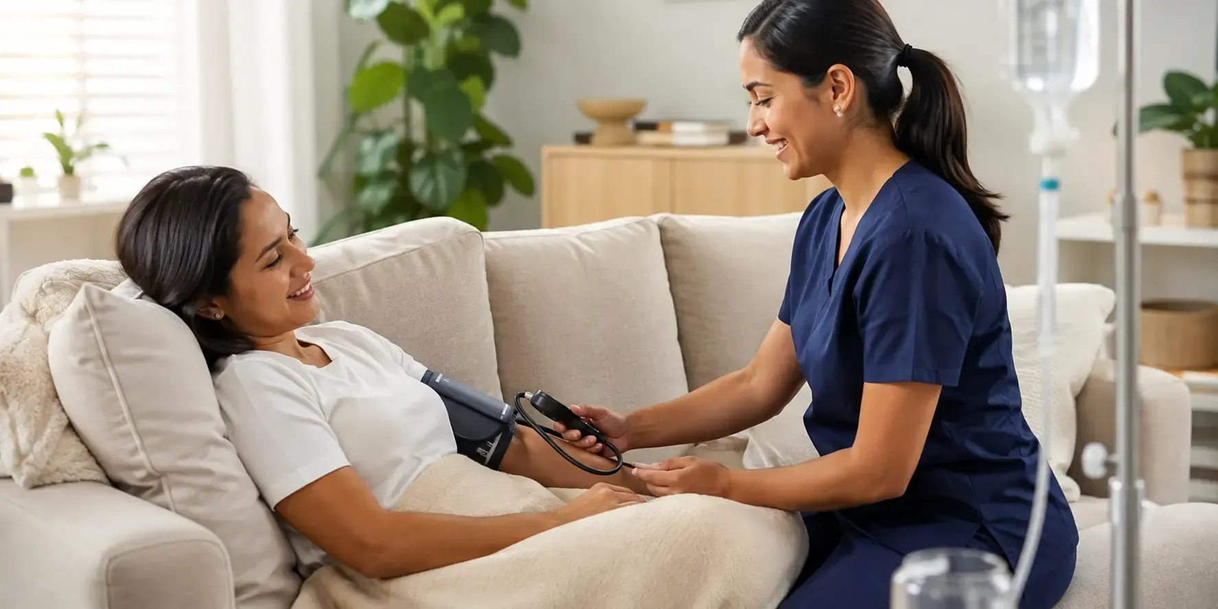 Smiling nurse checking the blood pressure of a client resting comfortably on a couch in a bright, modern care setting.